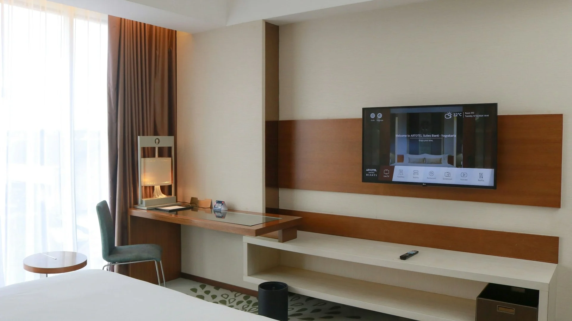 Kamar hotel modern dengan TV dinding menampilkan antarmuka informasi hospitality