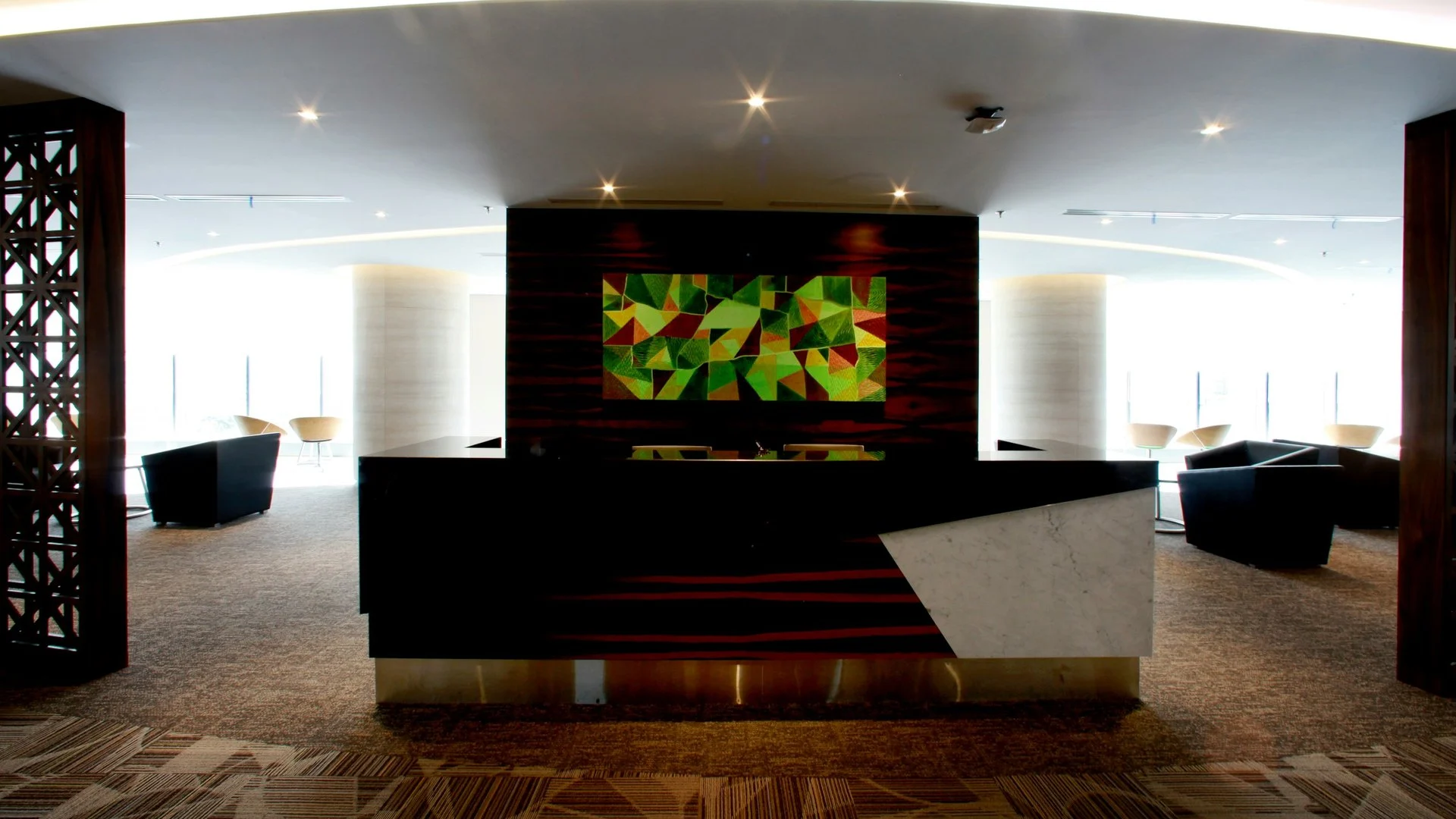 Lobi hotel modern dengan meja resepsionis dan panel visual di dinding