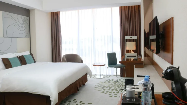 Kamar hotel modern dengan TV dinding di depan tempat tidur