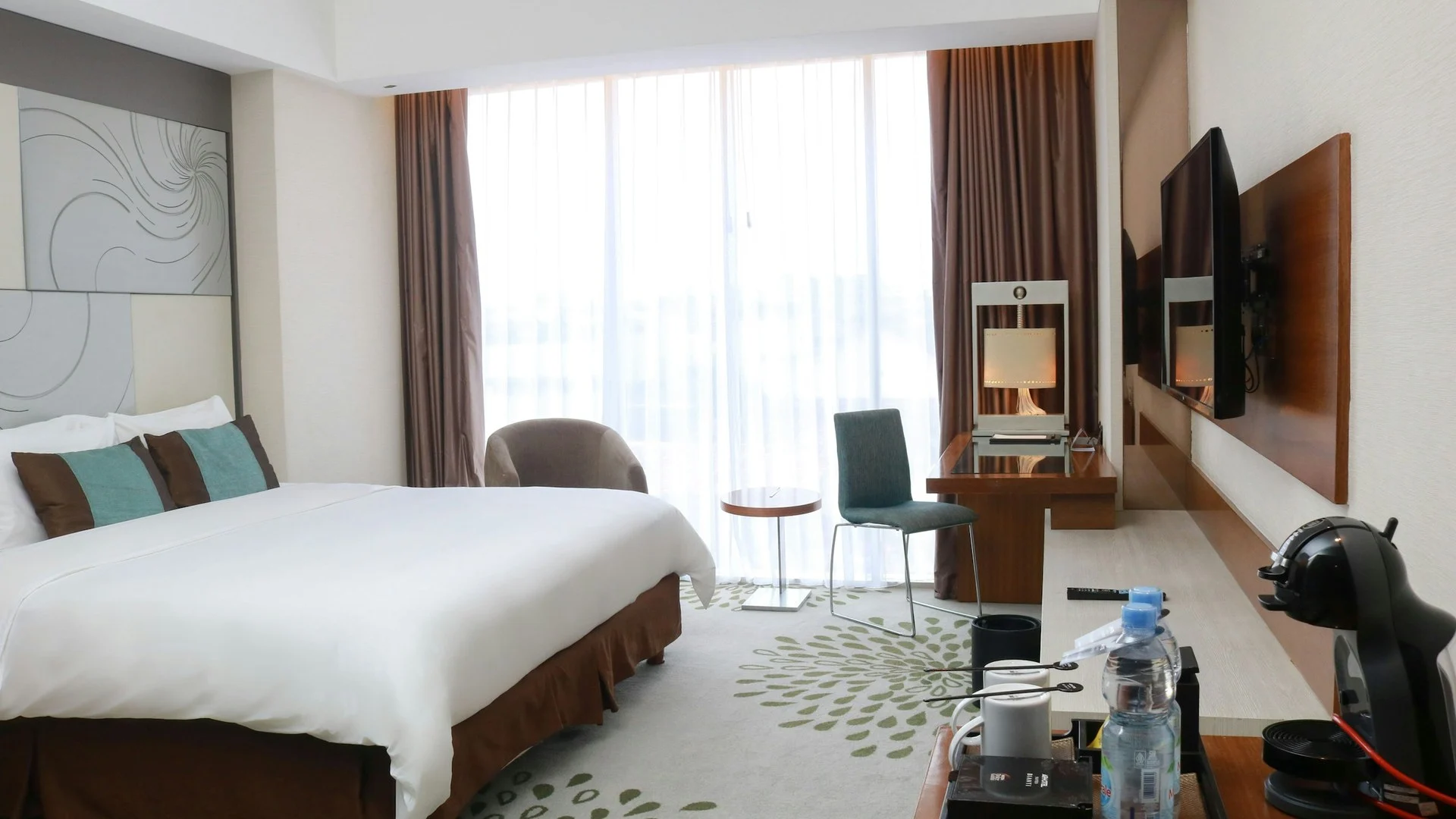 Kamar hotel modern dengan TV dinding di depan tempat tidur