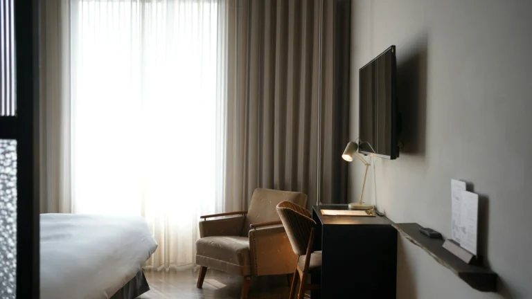 Kamar hotel butik dengan TV terpasang di dinding, kursi santai, dan meja kerja